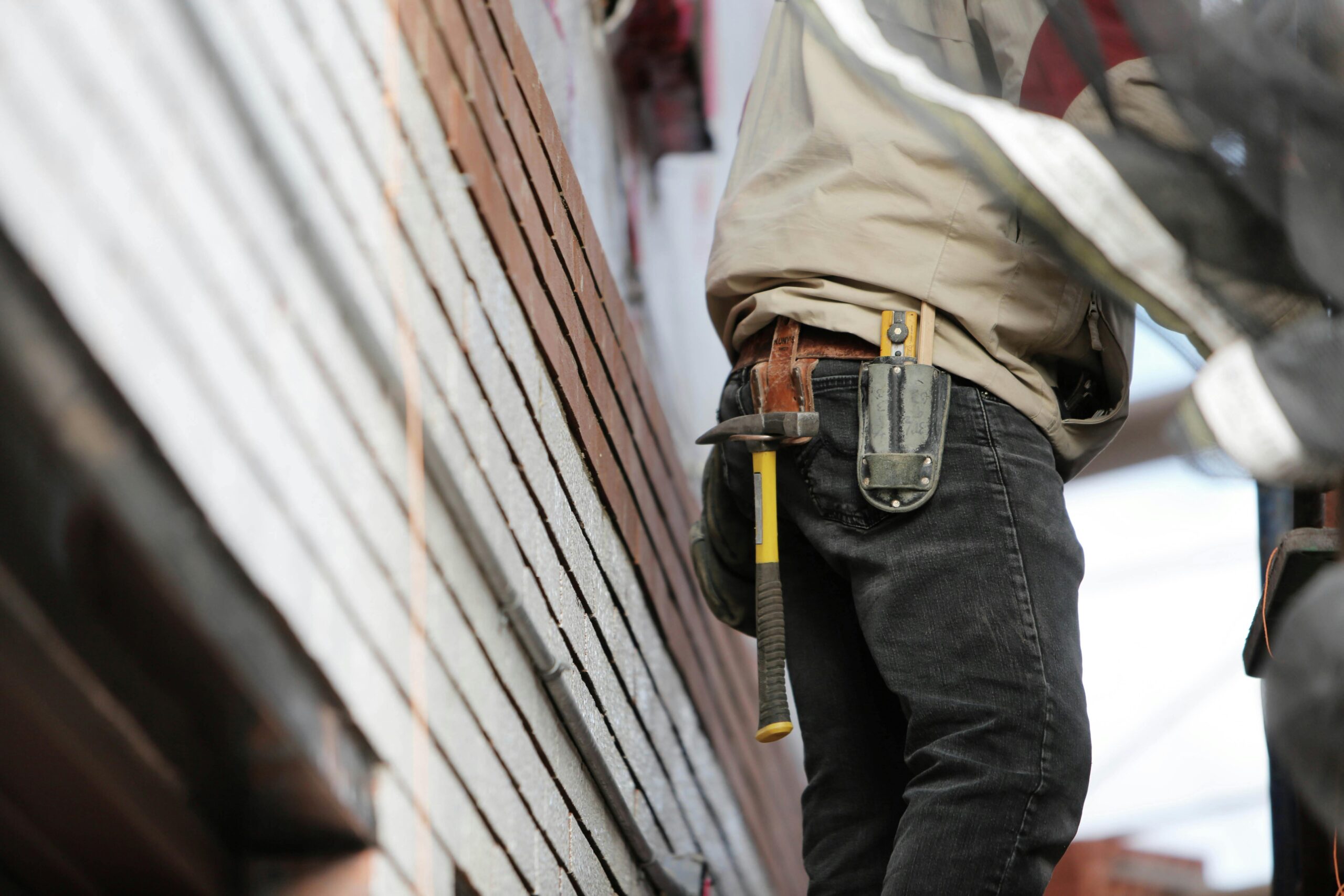 Rony's Home Solutions photo of a handyman servicing house siding and his tool belt