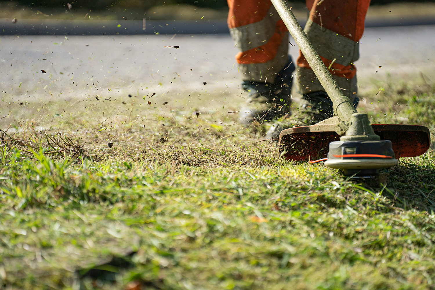 Rony's Home Solutions photo of a worker using a weed whacker on grass for lawn services